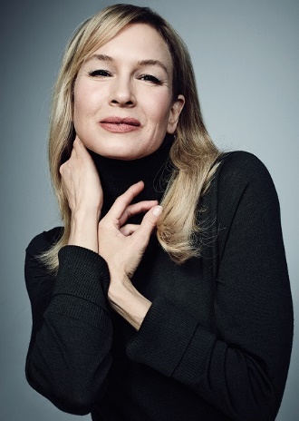 Renée Zellweger in a subtle pose wearing a black top with a smile.