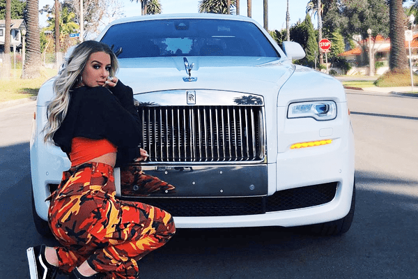 tana sitting in front of her white rolls royce