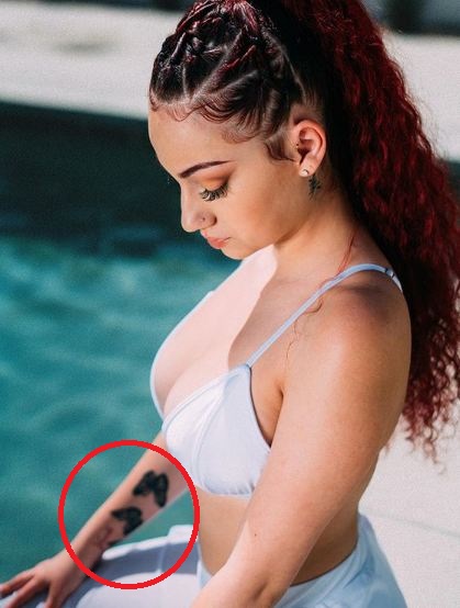 bergoli on the pool side showing her butterfly tattoo on her right arm 
