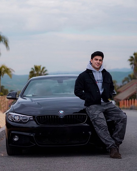 Diego Tinoco sitting on the hood of a BMW car.