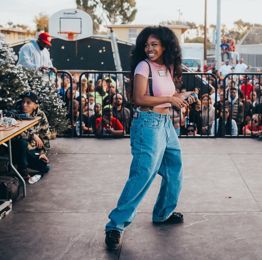 SZA wearing '90s baggy clothes while performing on stage.