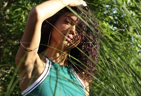 Sierra Capri posing for a photo with blades of grasses in front of her.