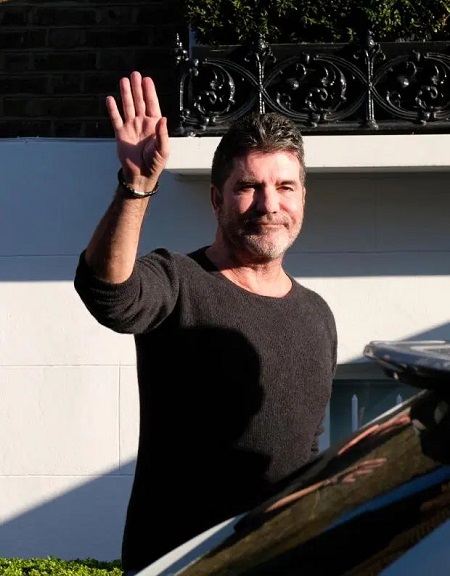 Simon Cowell putting on a brave face for the cameras when returning home.