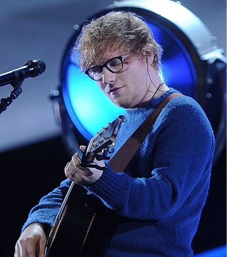 Ed Sheeran feeling lost in a song as he plays the guitar.