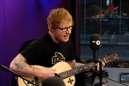 Ed Sheeran playing the guitar during the radio show.