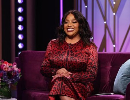 Sherri Shepherd in a blue jeans jacket poses in front of her Lexus.